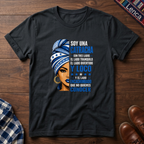 Black  t-shirt with a graphic of a woman with a headwrap and 'Soy Una Catracha' text on a wooden surface.
