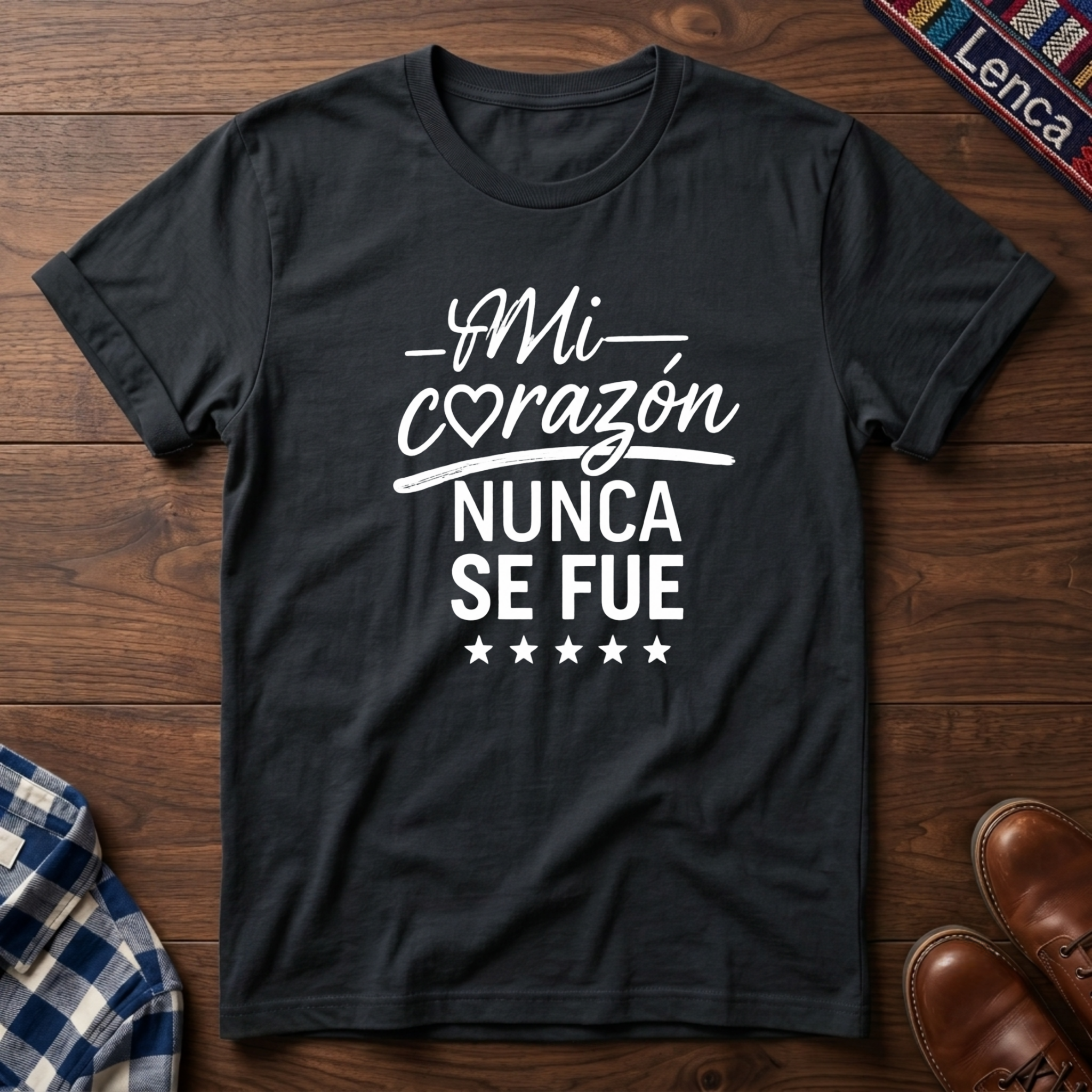 Black t-shirt with white 'Mi Corazon Nunca' text on a wooden surface.
