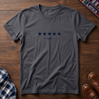 A charcoal short-sleeve crewneck t-shirt with a graphic of five dark blue stars and the text '— 504 —' on the chest, laid flat on a wooden surface.