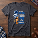 Dark Heather Gray t-shirt with a graphic of a woman with a headwrap and 'Soy Una Catracha' text on a wooden surface.