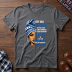 Graphite Heather t-shirt with a graphic of a woman with a headwrap and 'Soy Una Catracha' text on a wooden surface.