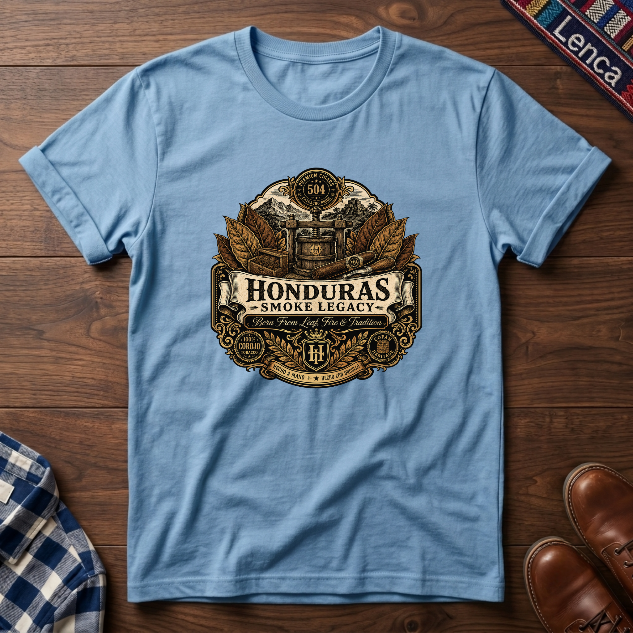 Light blue t-shirt with 'Honduras Smoke Legacy' graphic on a wooden surface.