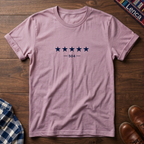 Light pink short-sleeve crewneck t-shirt with a graphic of five dark blue stars and the text '— 504 —' on the chest, laid flat on a wooden surface.