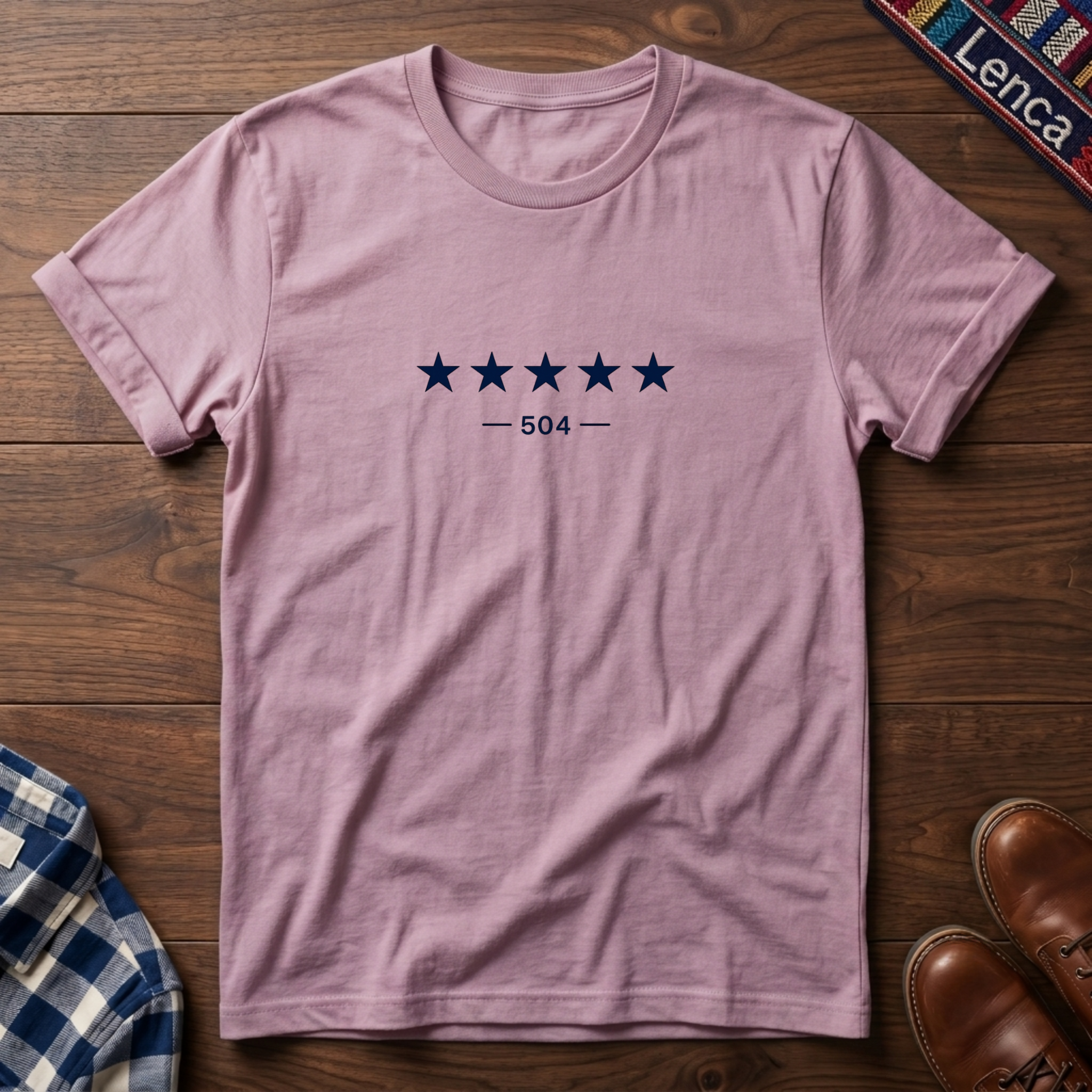Light pink short-sleeve crewneck t-shirt with a graphic of five dark blue stars and the text '— 504 —' on the chest, laid flat on a wooden surface.