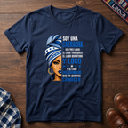 Navy blue t-shirt with a graphic of a woman with a headwrap and 'Soy Una Catracha' text on a wooden surface.