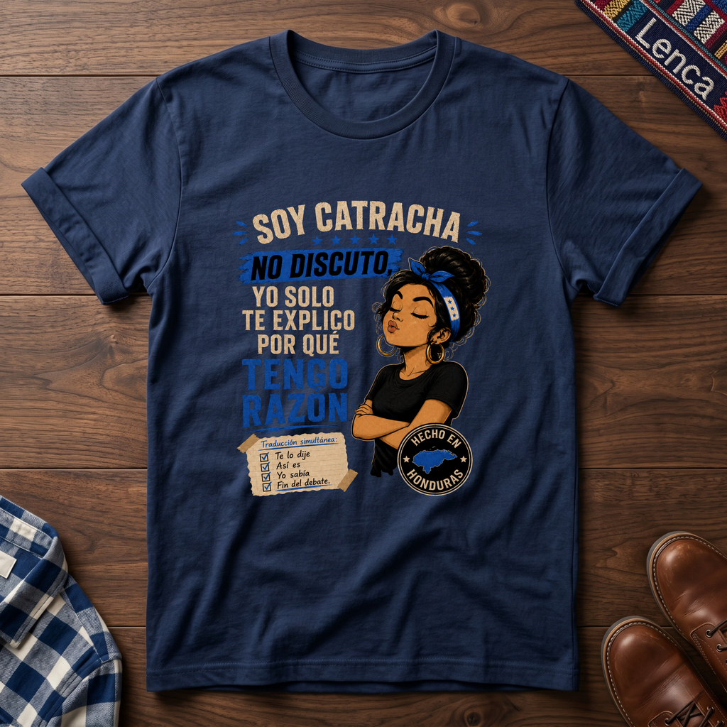 A navy graphic t-shirt laid flat on a dark wood background, featuring a printed design with the text 'SOY CATRACHA NO DISCUTO'.