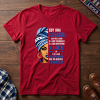 Red t-shirt with a graphic of a woman with a headwrap and 'Soy Una Catracha' text on a wooden surface.