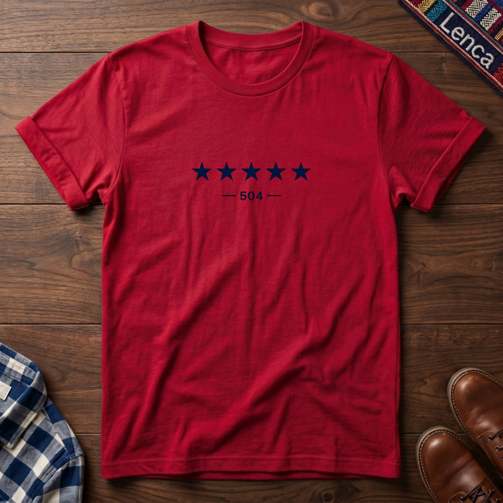 A red short-sleeve crewneck t-shirt with a graphic of five dark blue stars and the text '— 504 —' on the chest, laid flat on a wooden surface.