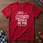 Red t-shirt with white 'Mi Corazon Nunca' text on a wooden surface.