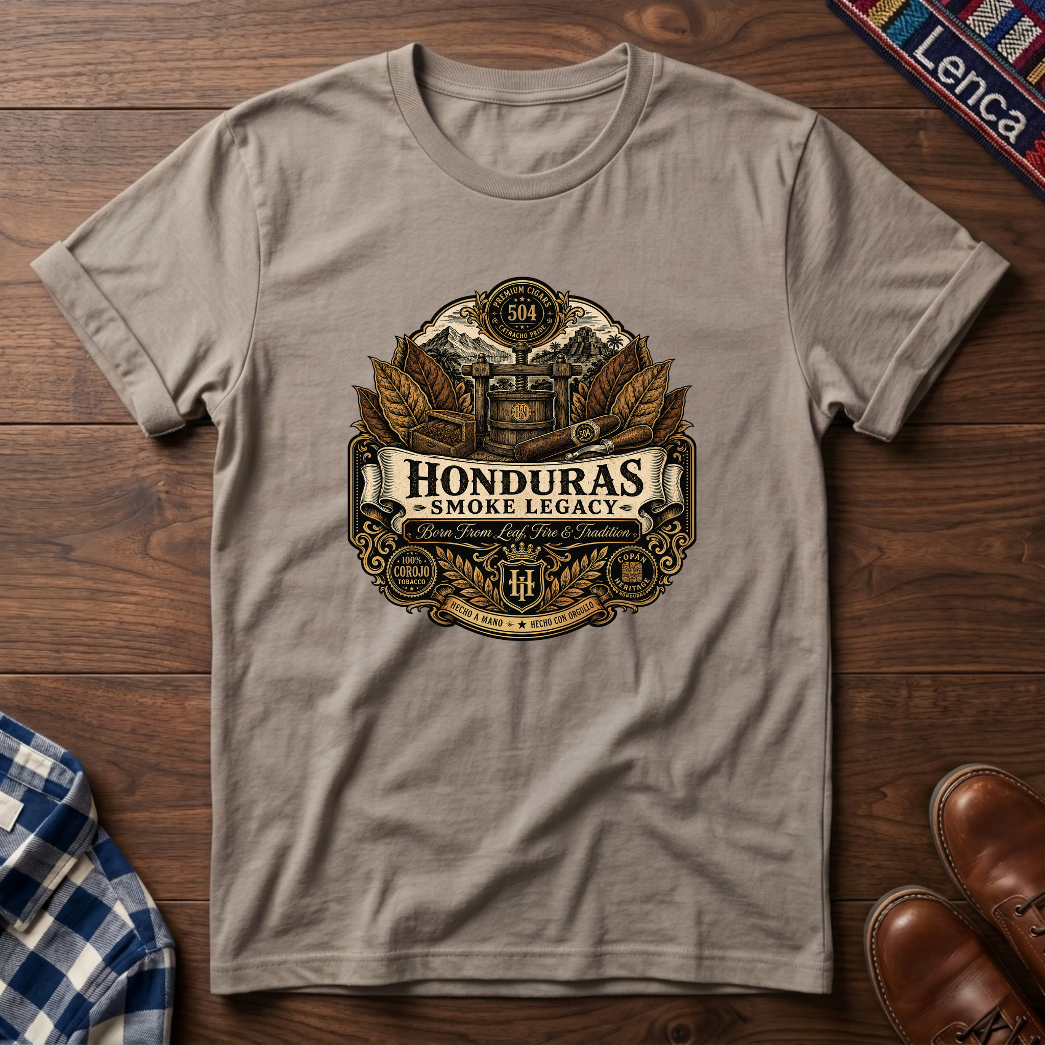 Sand t-shirt with 'Honduras Smoke Legacy' graphic on a wooden surface.