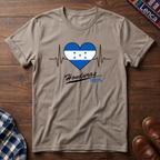 Sand t-shirt with a heart design featuring Honduras' flag and 'Honduras 100%' text on a wooden surface.