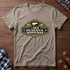 Sand t-shirt with 'La 504 Reserva Honduras' graphic design on a wooden surface.