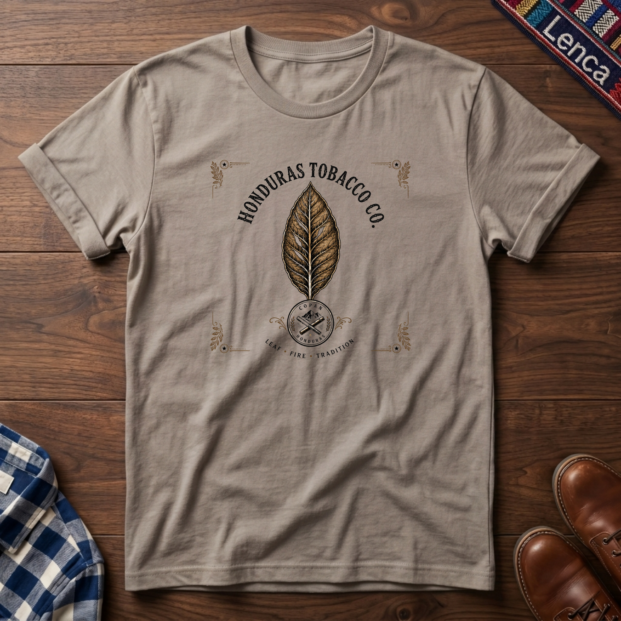 Sand t-shirt with 'Honduras' text and leaf graphic on a wooden surface.