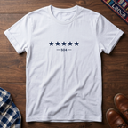 White short-sleeve crewneck t-shirt with a graphic of five dark blue stars and the text '— 504 —' on the chest, laid flat on a wooden surface.