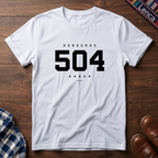 A white short-sleeve crewneck t-shirt with 'HONDURAS 504' printed in black on the front, laid flat on a dark wood background.